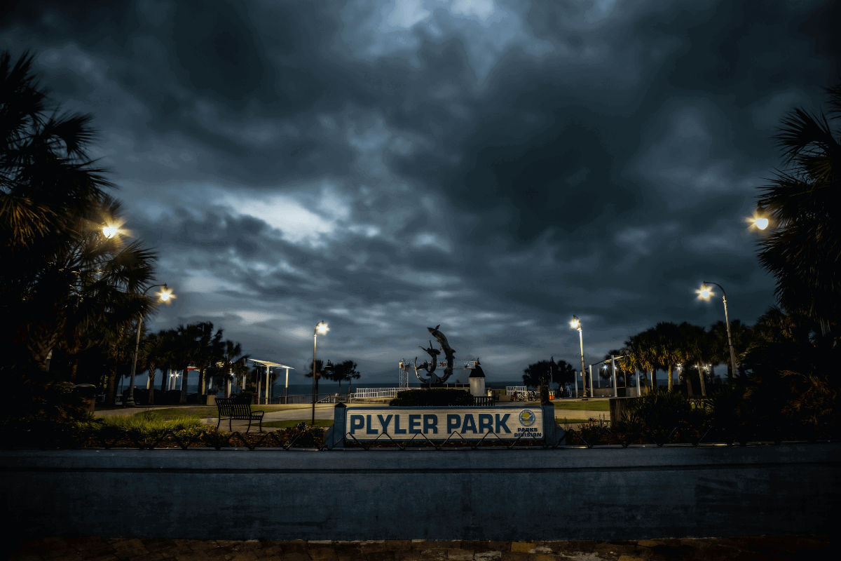 Plyler Park ghostly illuminated by overhead lamps and a grey/black night sky. Trees lurk on either side.